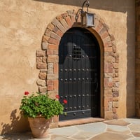 Arched Black Plank Door With Studs, Brick Frame, and Lantern