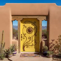 Bright Yellow Plank Door With Wrought Iron Sun Face in Southwestern Setting
