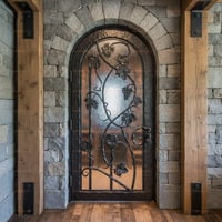 Arched Black Metal Door With Glass Vine Design Set in Stone Archway